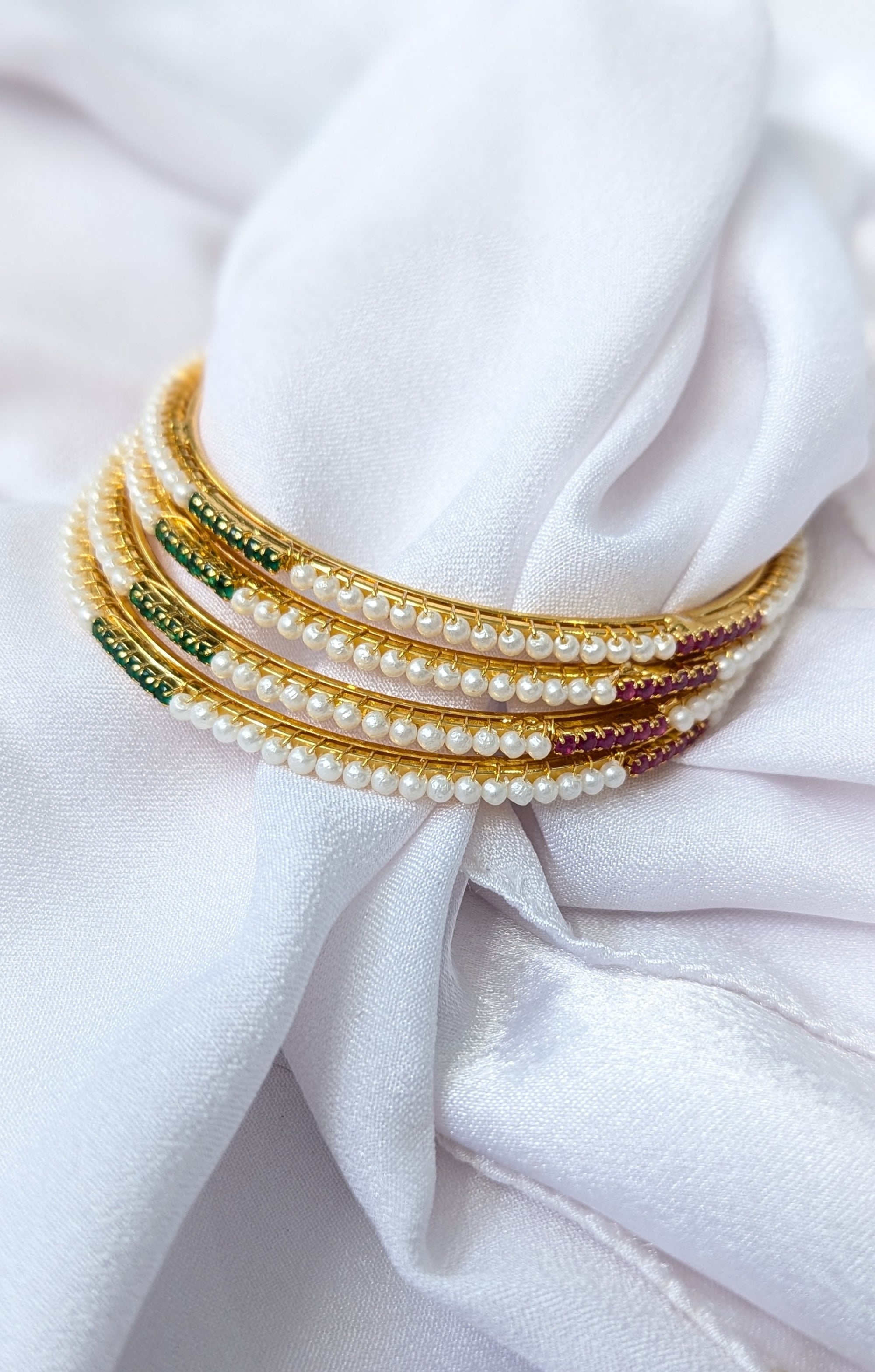 Set of pearl and beaded bracelets on a white fabric background