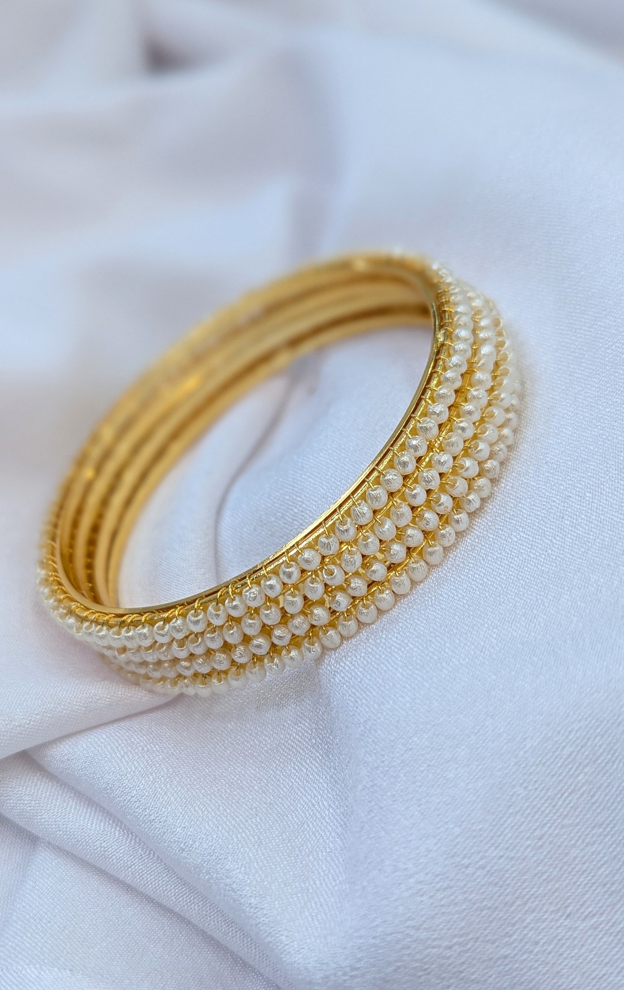 Gold and pearl bracelet on a white fabric background