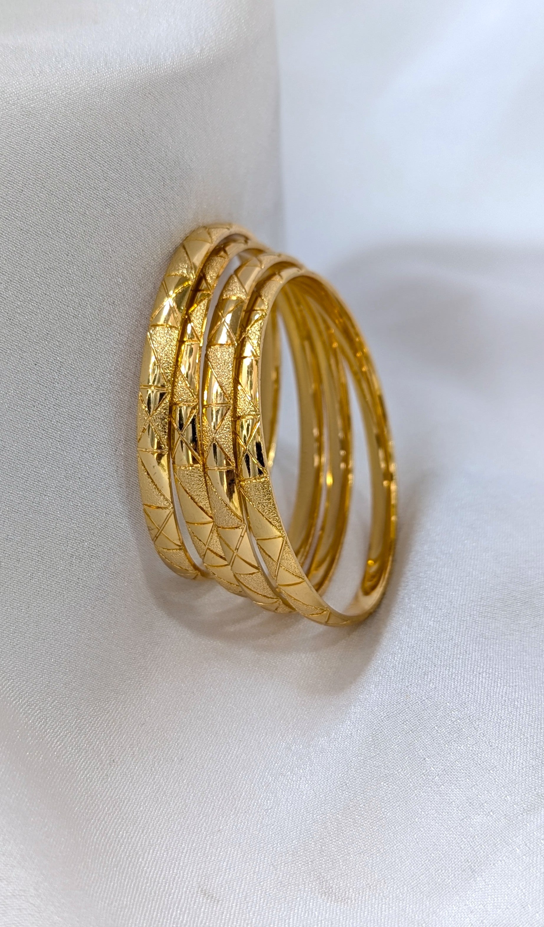 Three gold rings with textured design on a white background