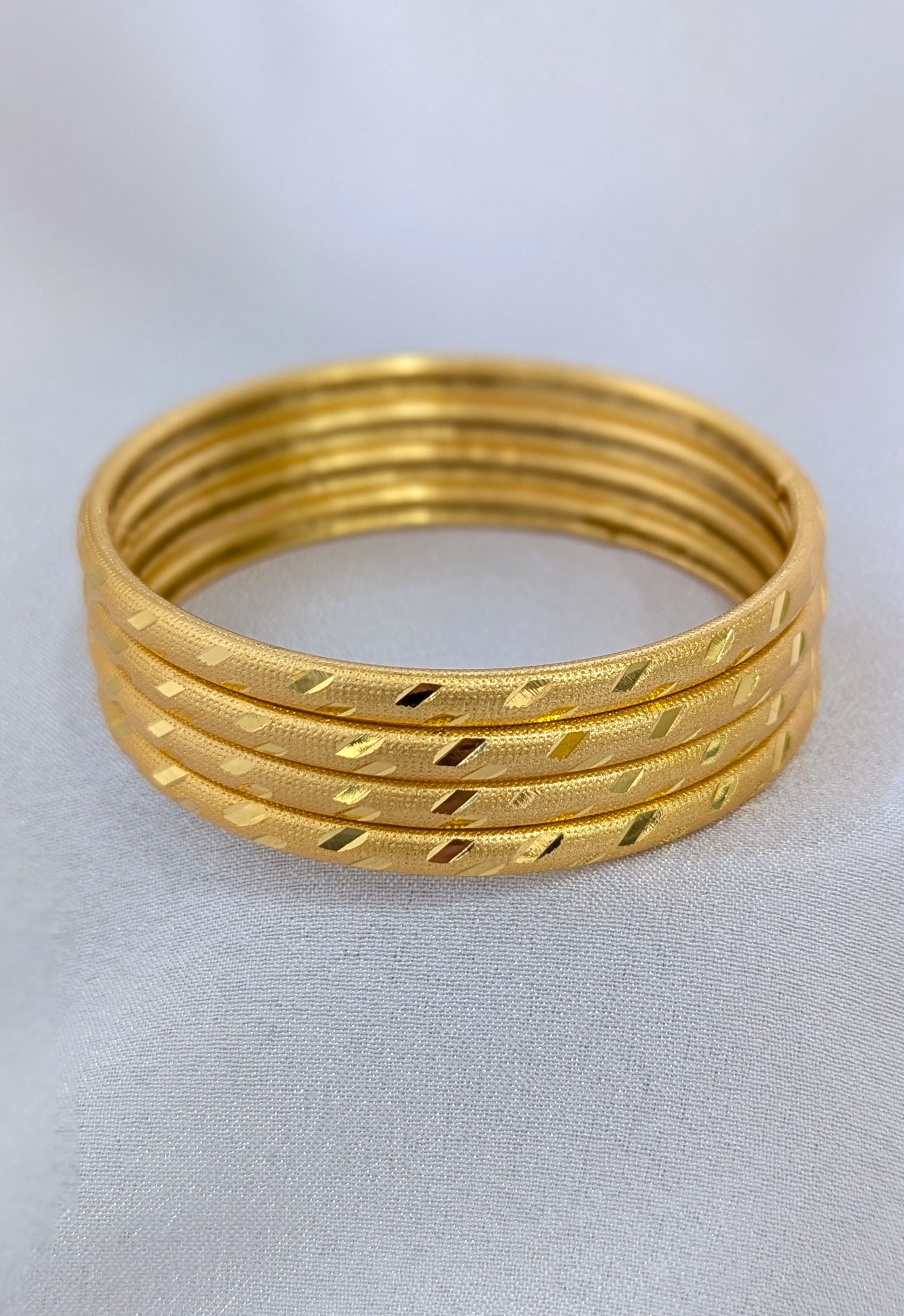Set of gold bangles on a light gray background