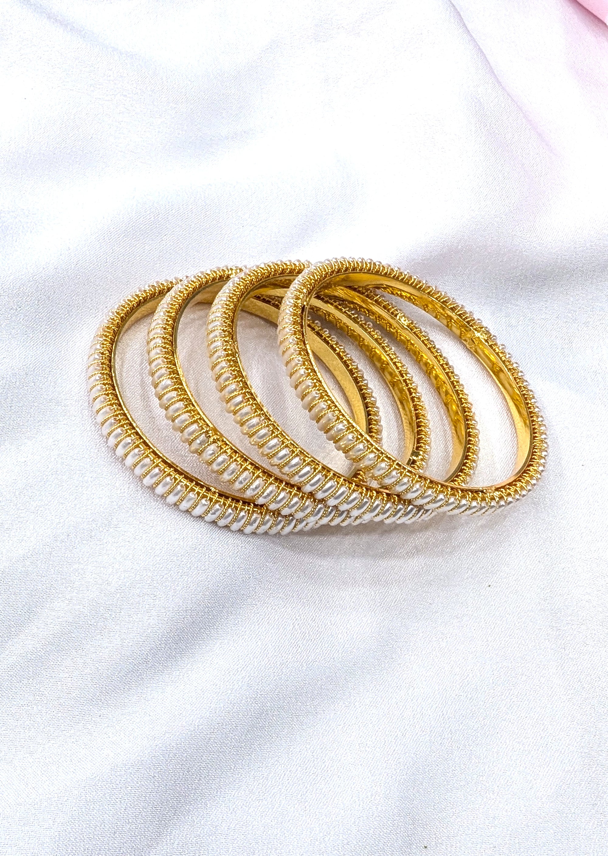 Set of gold bangles on a white fabric background
