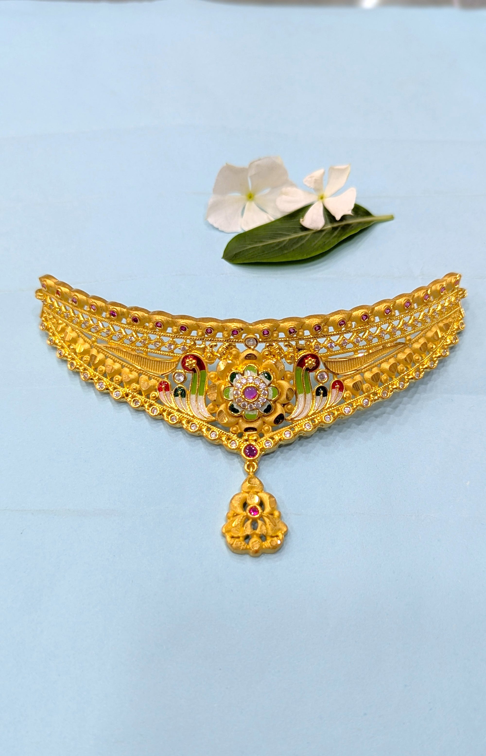 Gold necklace with decorative elements on a light blue background