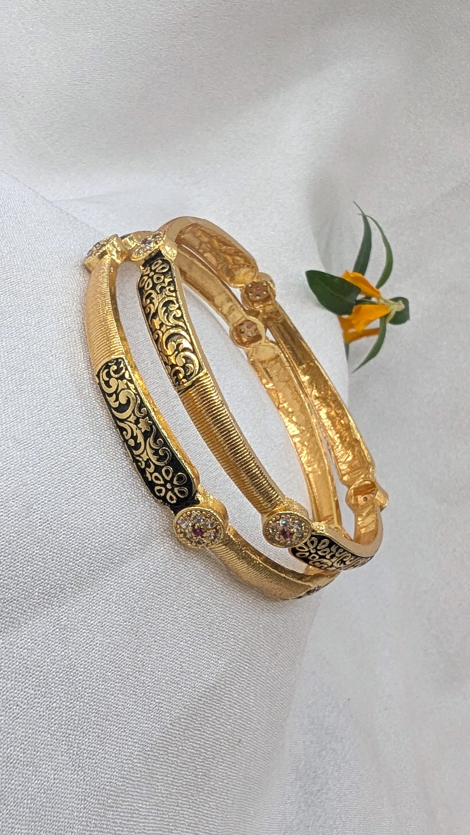Gold bangles with intricate designs on a light gray background