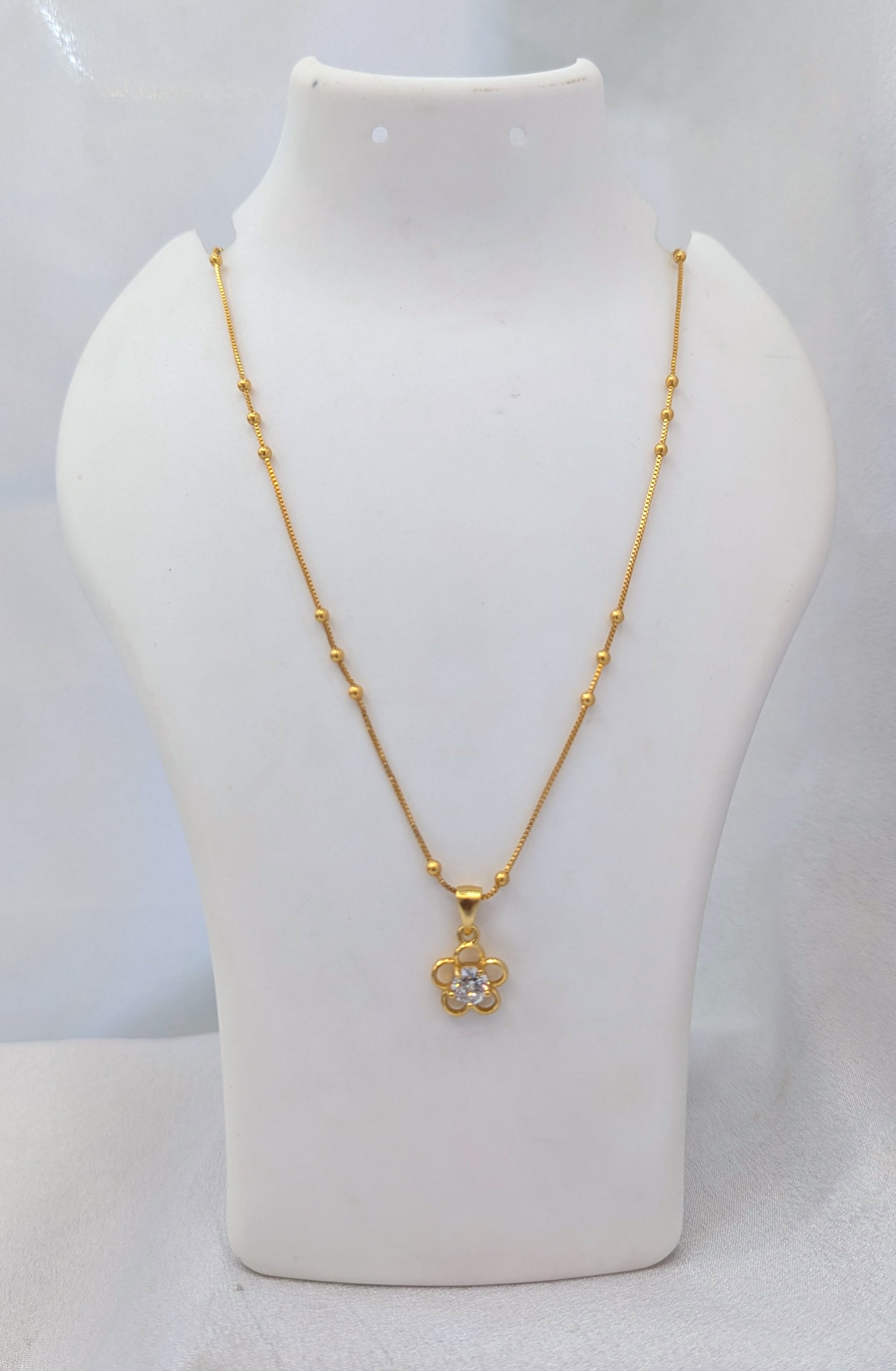 Gold necklace with a pendant on a mannequin bust against a white background