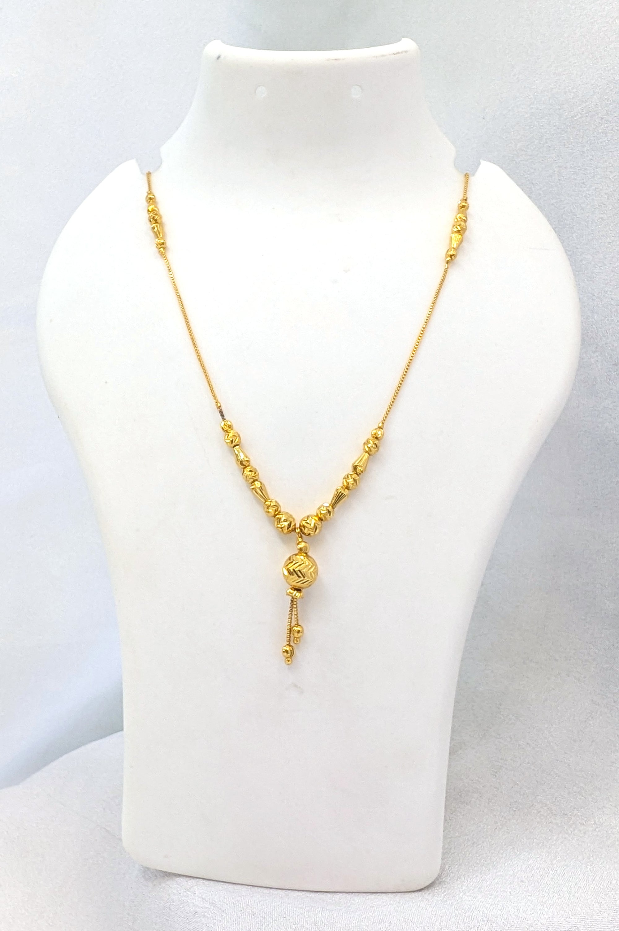 Gold necklace on a white mannequin bust against a light gray background