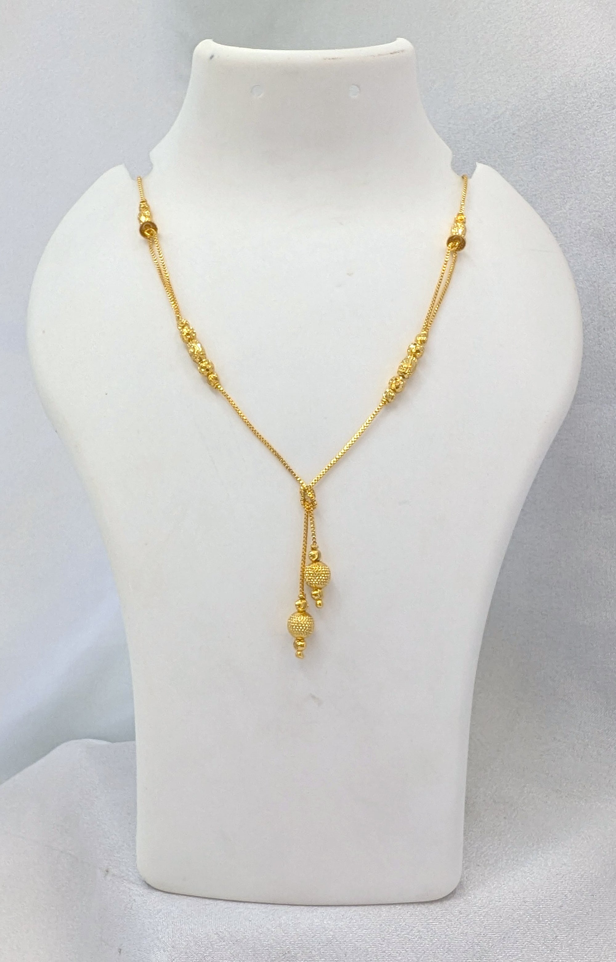 Gold necklace on a white mannequin bust against a light gray background