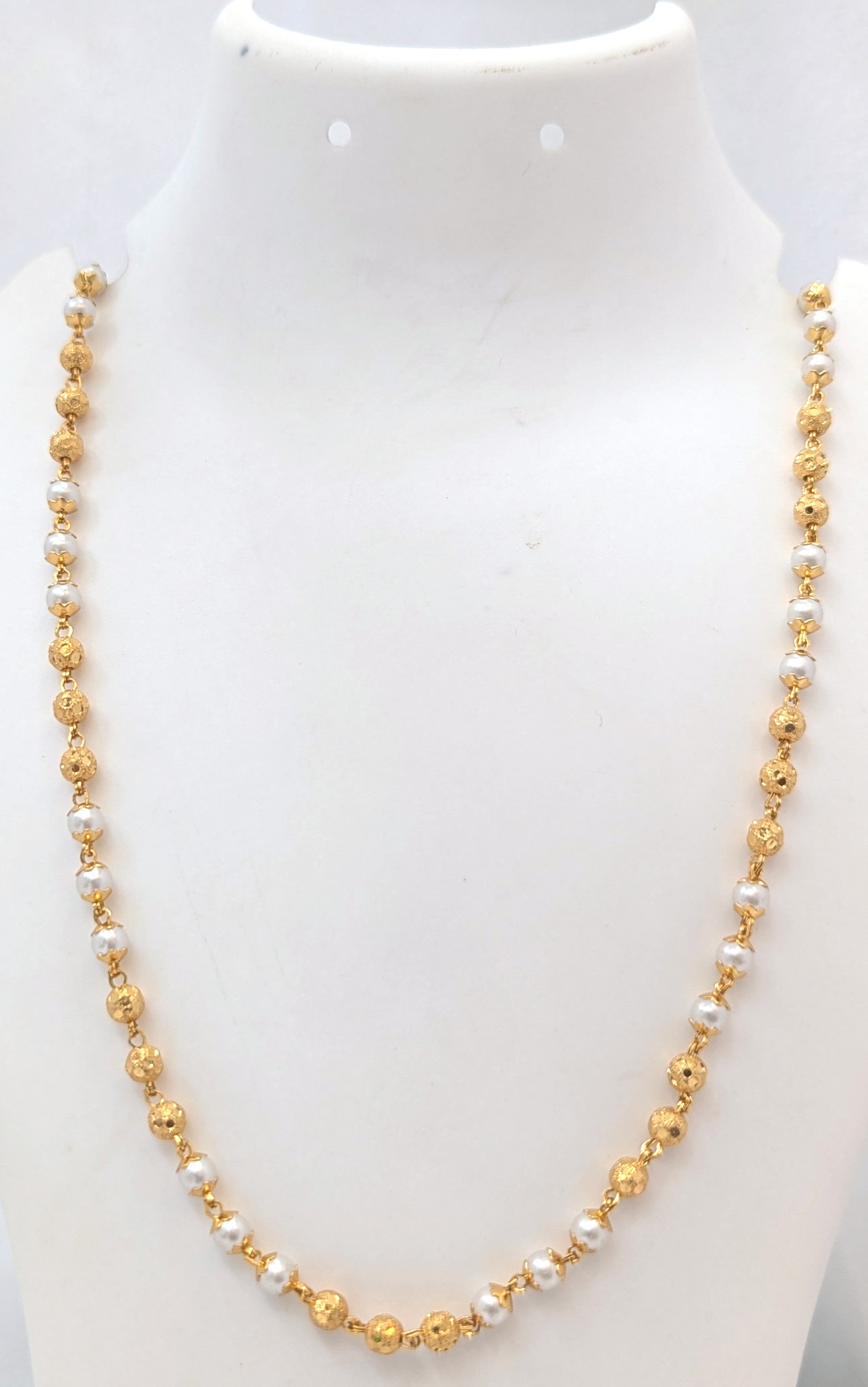 Gold and pearl necklace on a mannequin with a white background