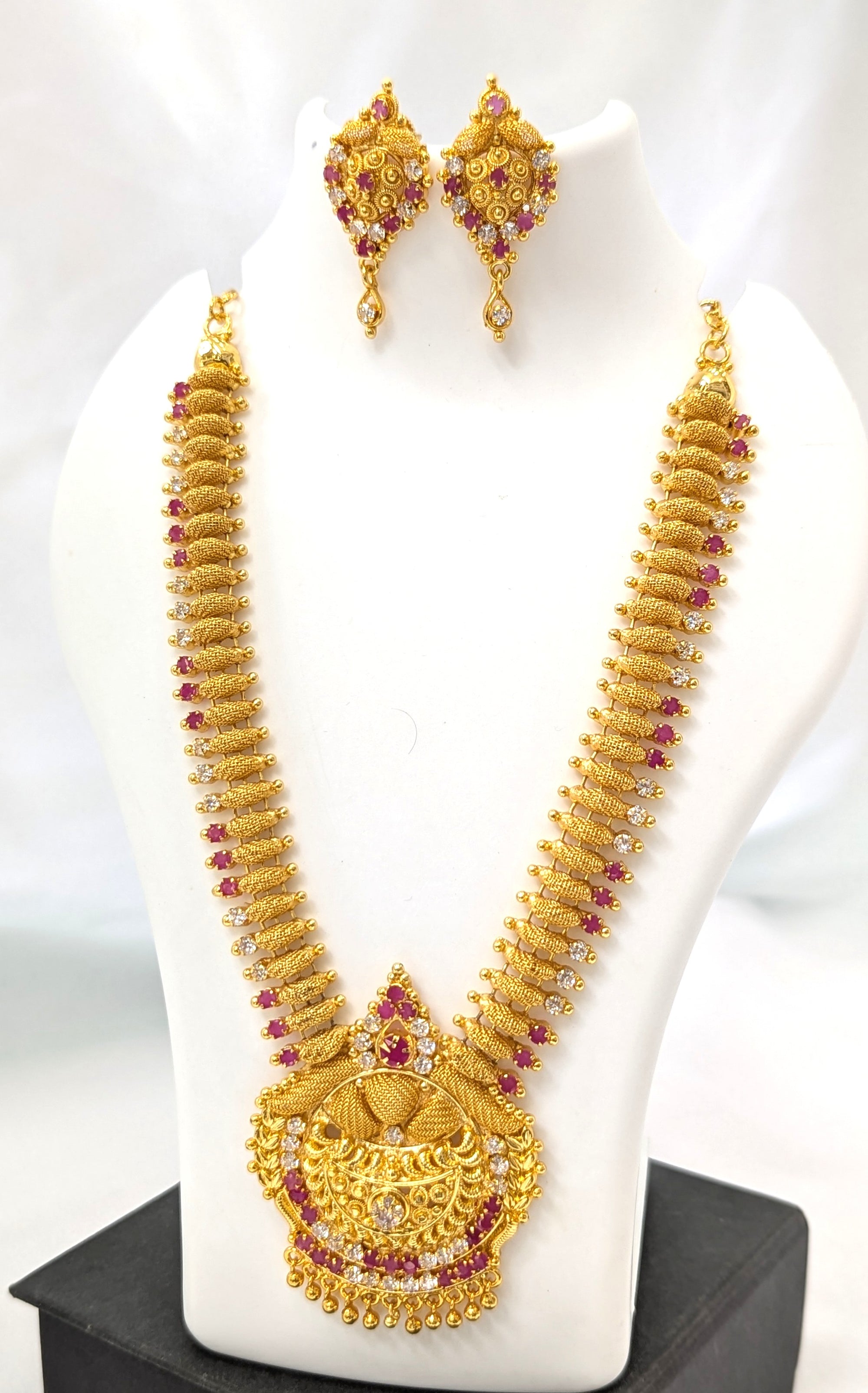 Gold necklace and earrings set on a white mannequin with a gray background