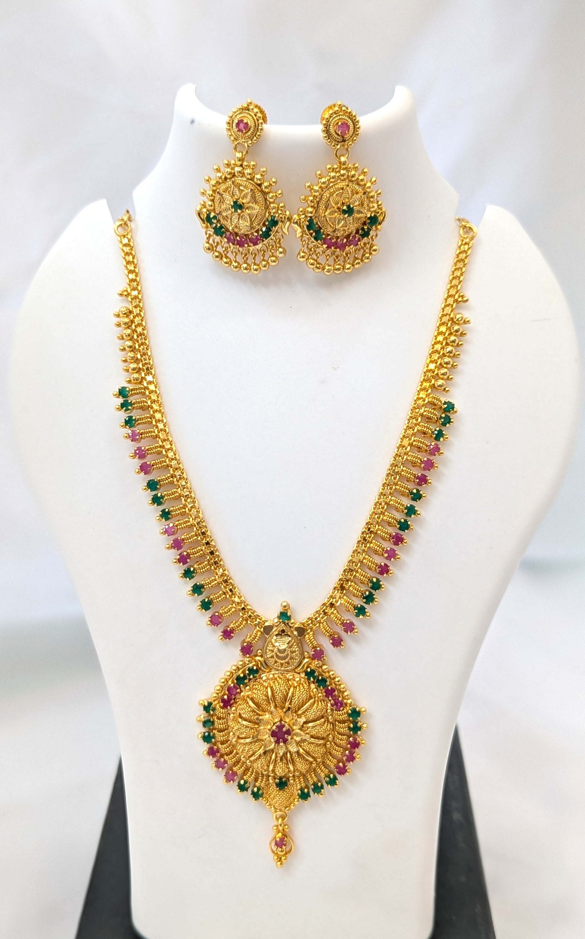 Gold necklace and earrings set on a mannequin with a white background